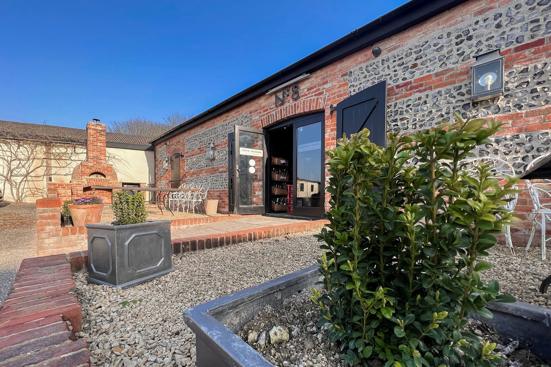 view of seating area outside beautiful red brick converted barn with double doors