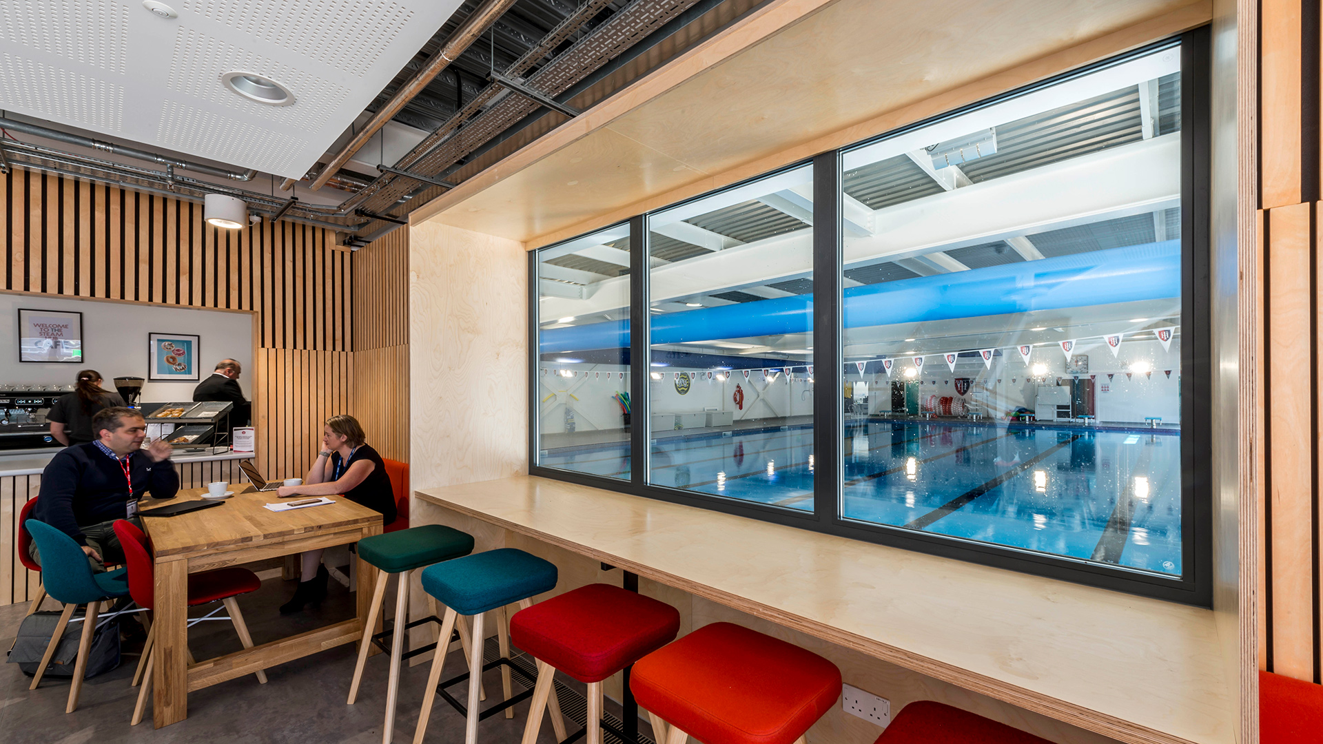 interior cafe with seating overlooking alarge indoor pool