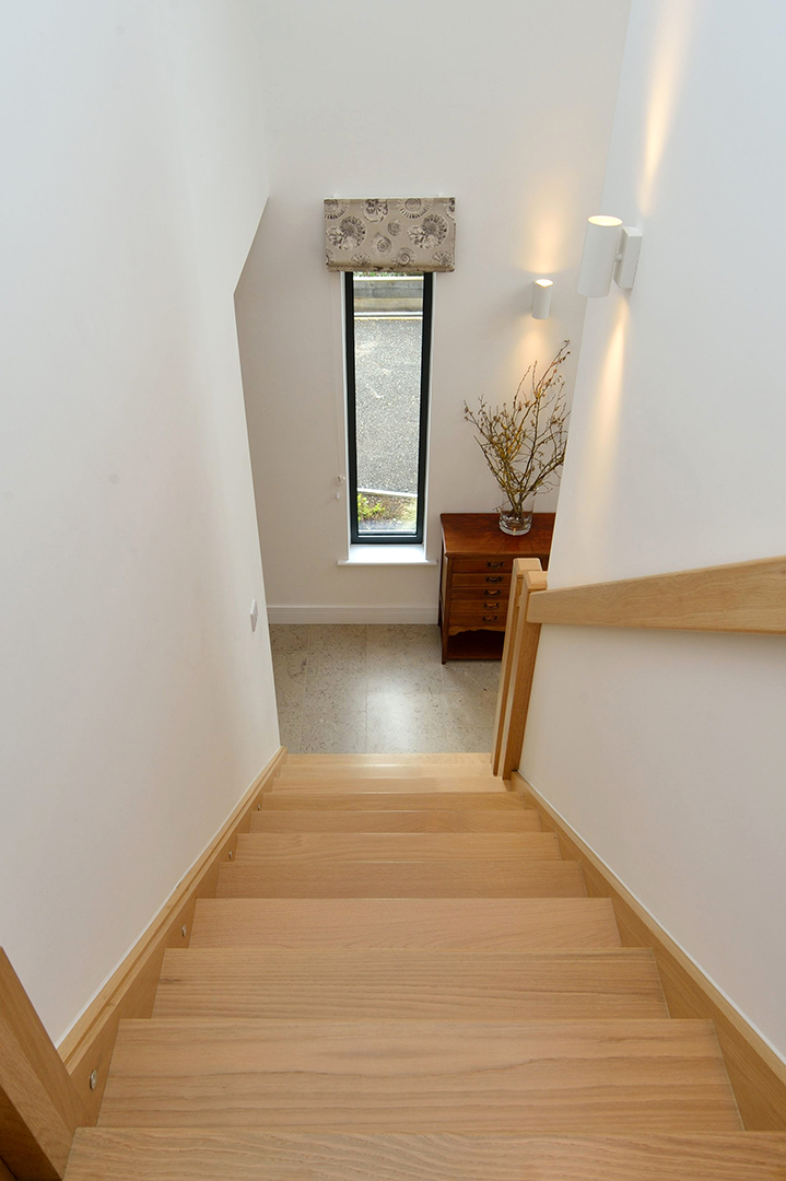 view from top of modern wooden staircase looking down to ground floor with rectangle feature window