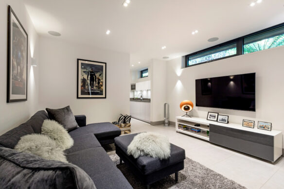 living room with grey sofa onlooking television on wall