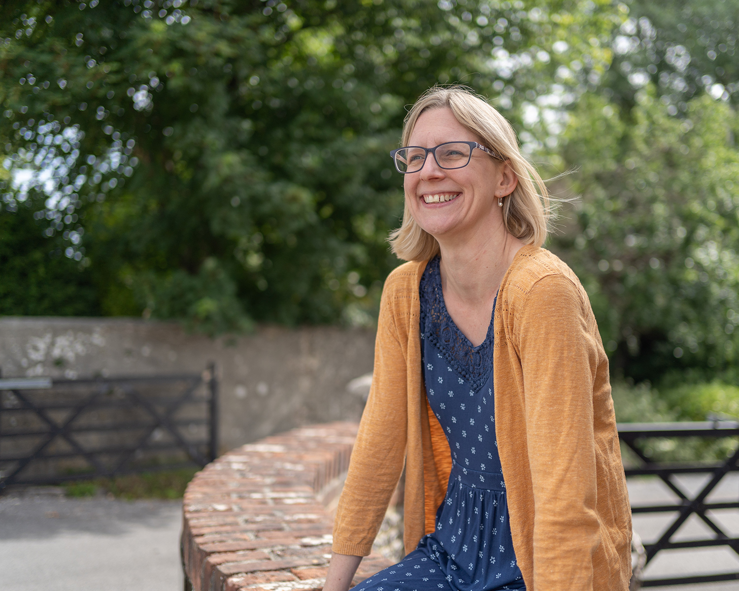 Kathryn Flint, sat on a wall smiling