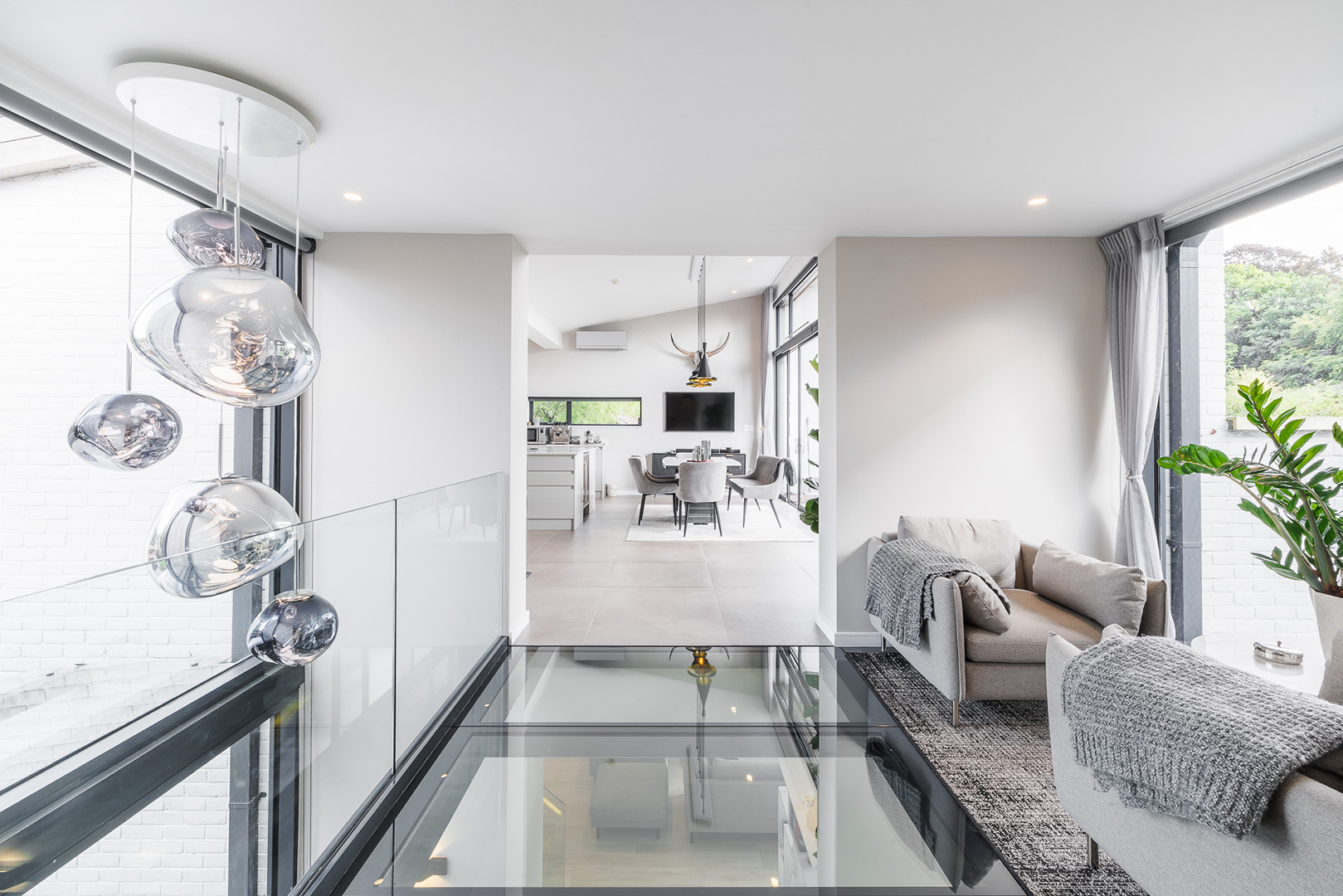 First floor balcony with glass floor looking onto open plan kitchen dining room