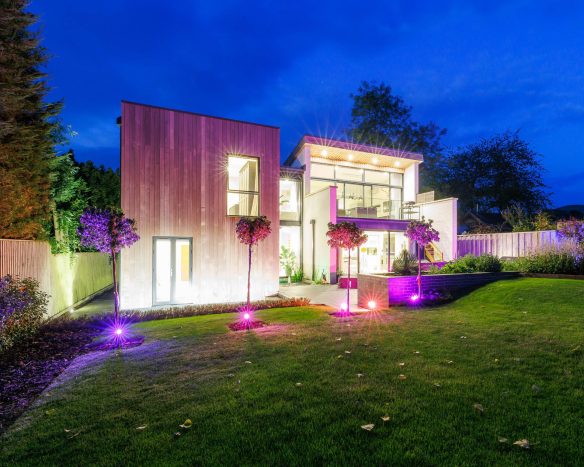 timber and brick house lit up and night with colourful lights