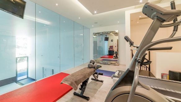 gym area overlooking swimming pool with glass paneling