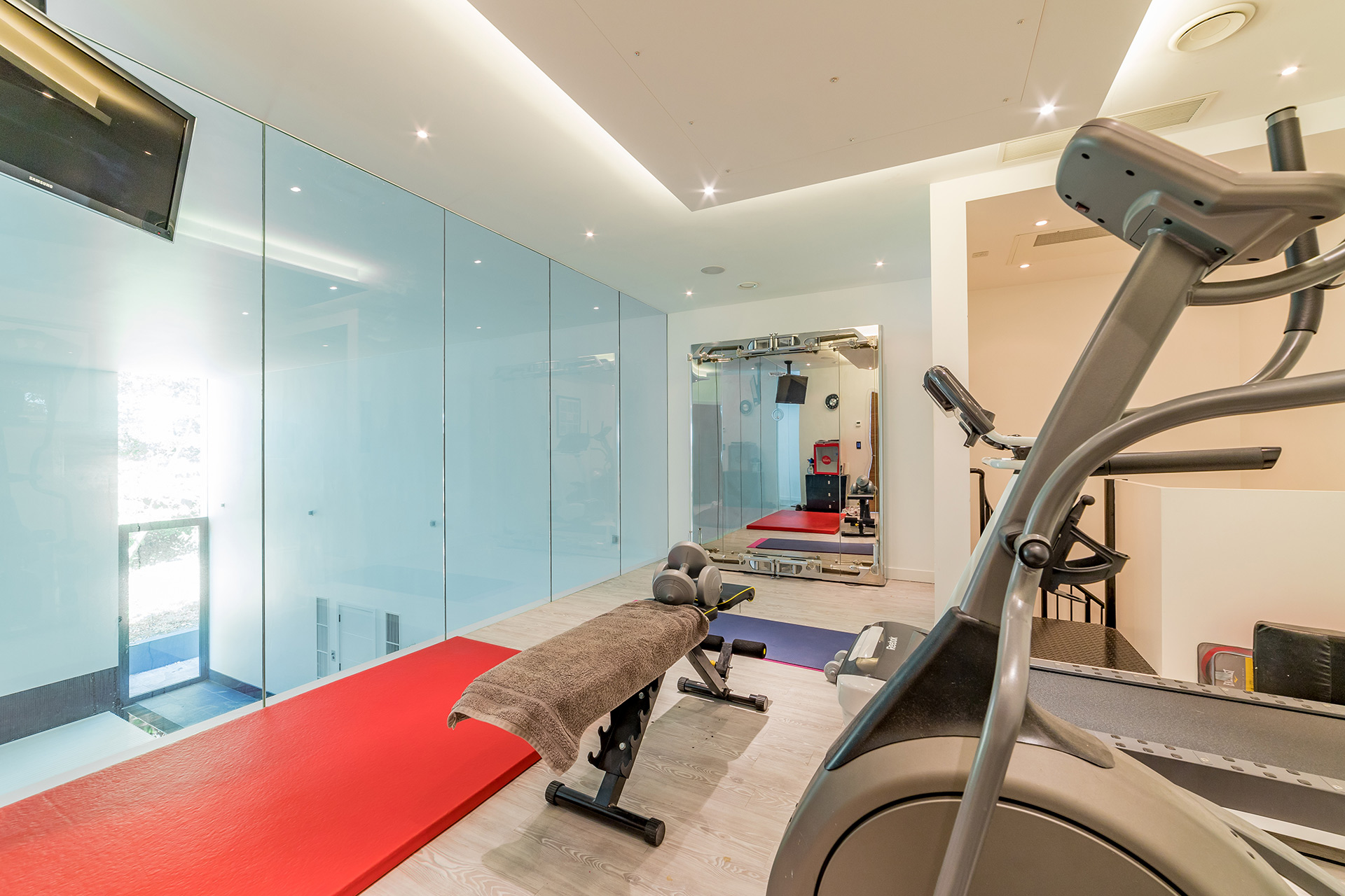 gym area overlooking swimming pool with glass paneling