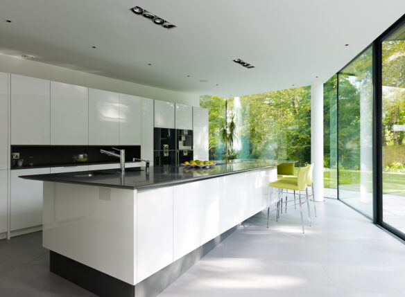 modern kitchen interior with large floor to ceiling windows overlooking green garden