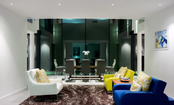 open plan living and dining area with double height glass frontage windows at night