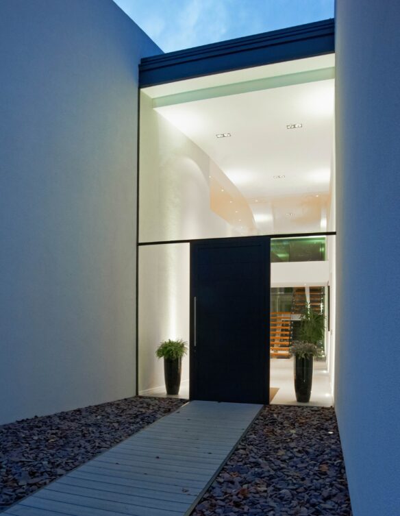 Glass entrance to modern house at night with lights on