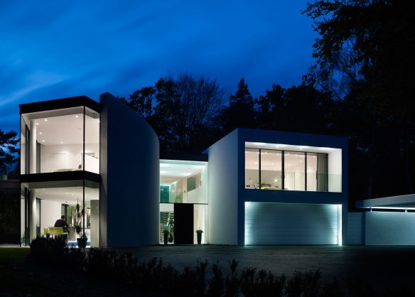 view from front garden of modern house at night with lights on