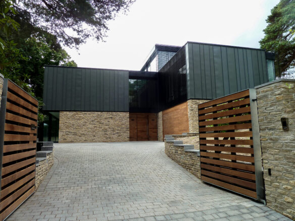 entrance to sloping driveway leading to large modern house