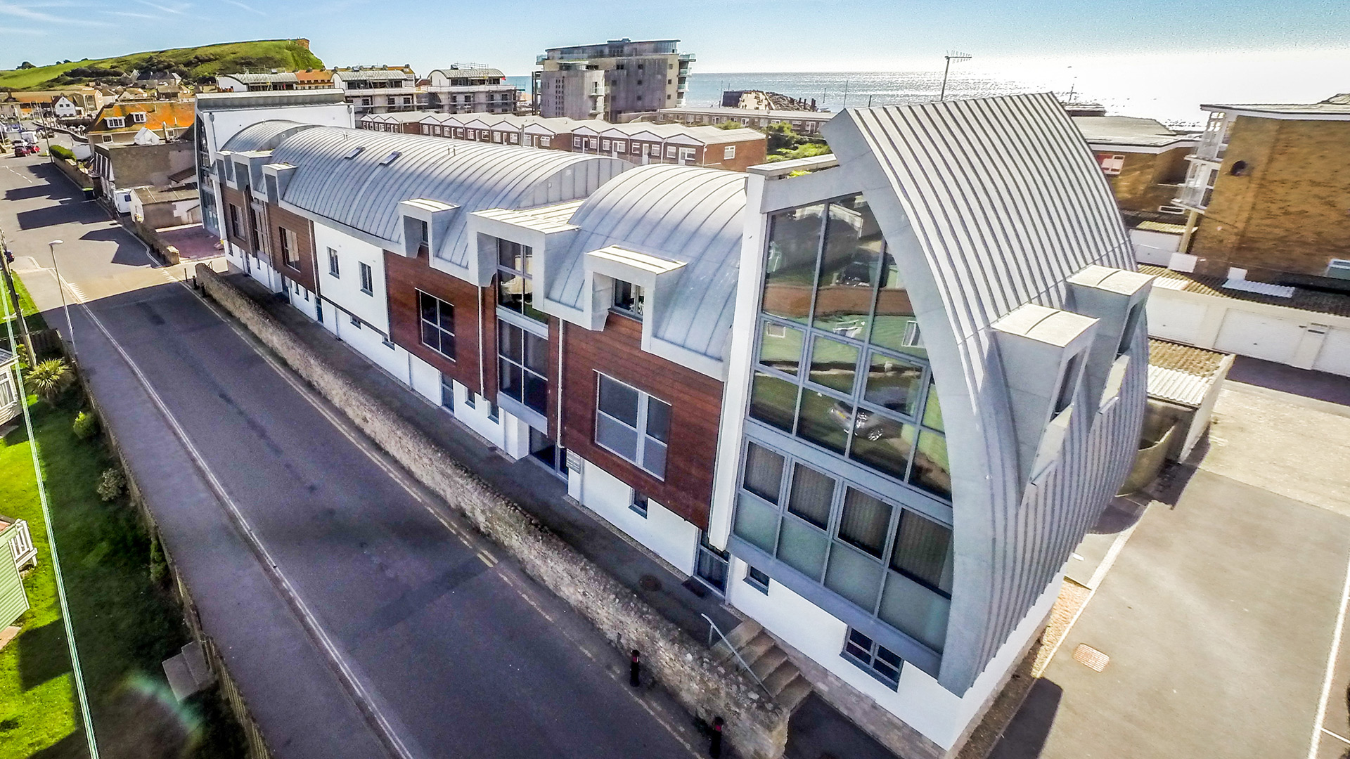 aerial view of building with curved roof and sea views