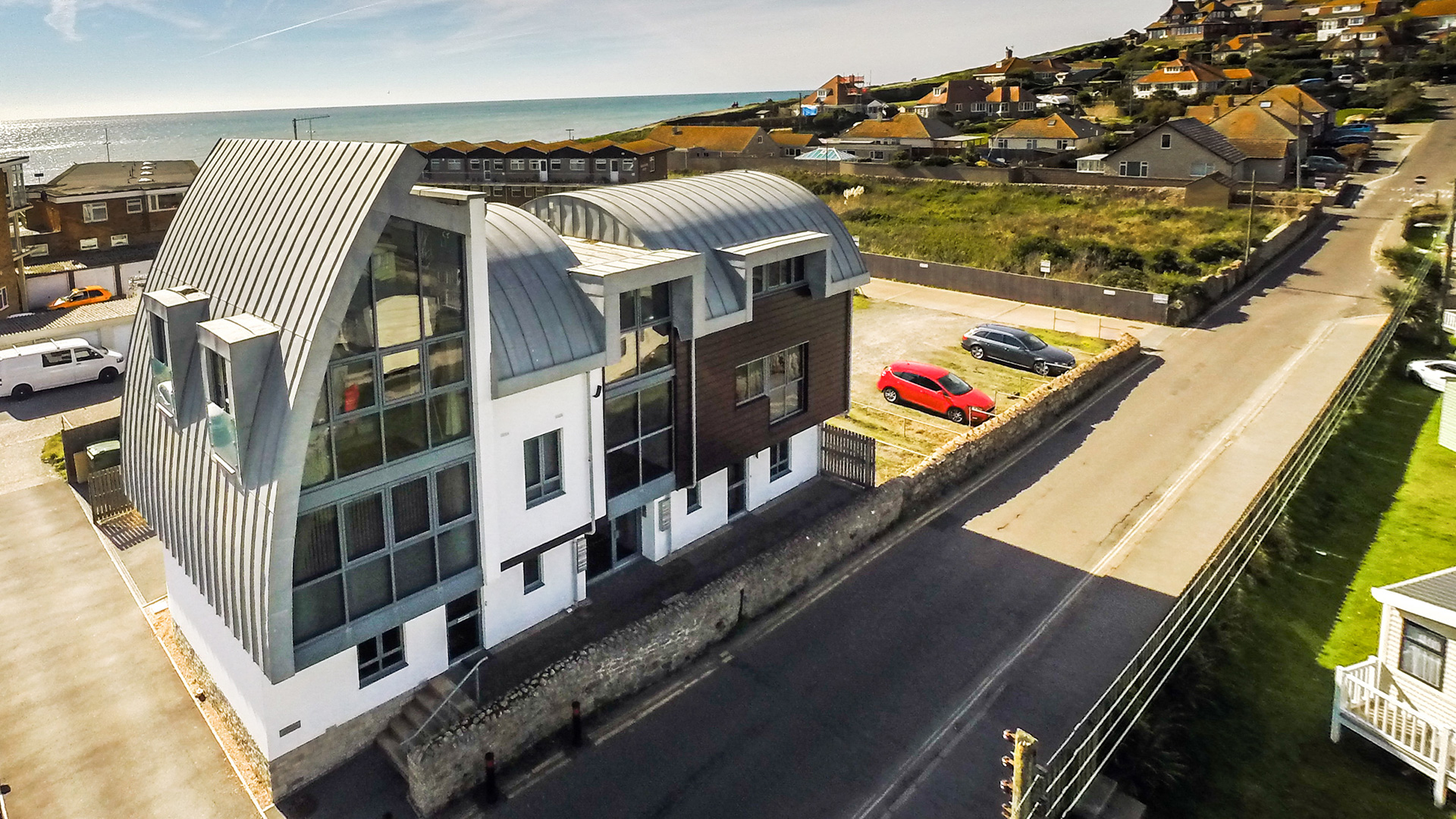 aerial view of building with curved roof and sea views