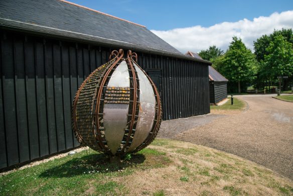 large garden artwork structure in front of black wooden building