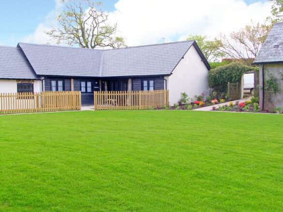 rear view of barn conversion with large lawn and fenced patio