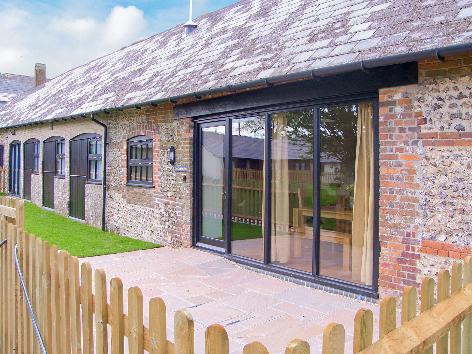 rear view of red brick and stone barn conversion and fenced patio