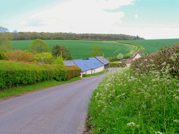 street view looking onto large barn conversion with beautiful countryside behind