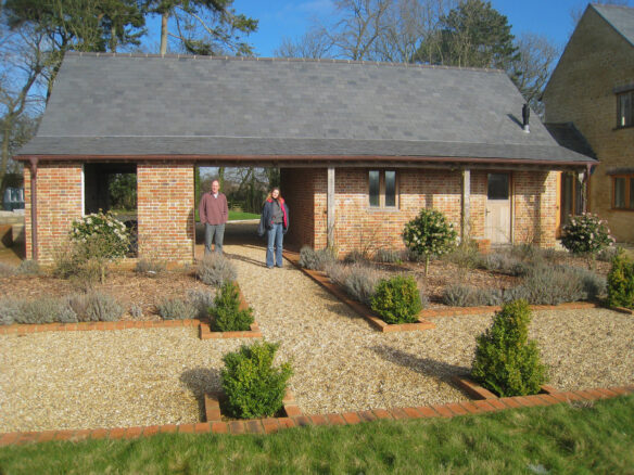 front view of red brick barn with lovely garden in front