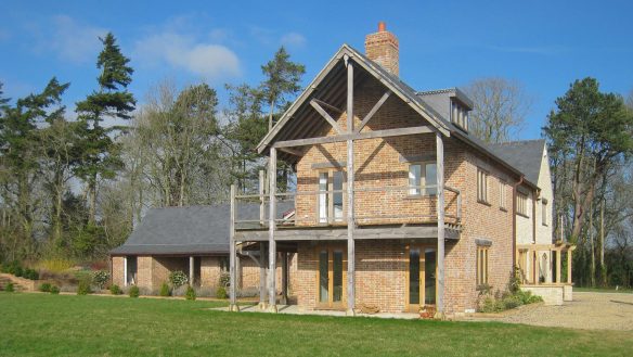 side view of red brick and stone house with large gable end and balcony