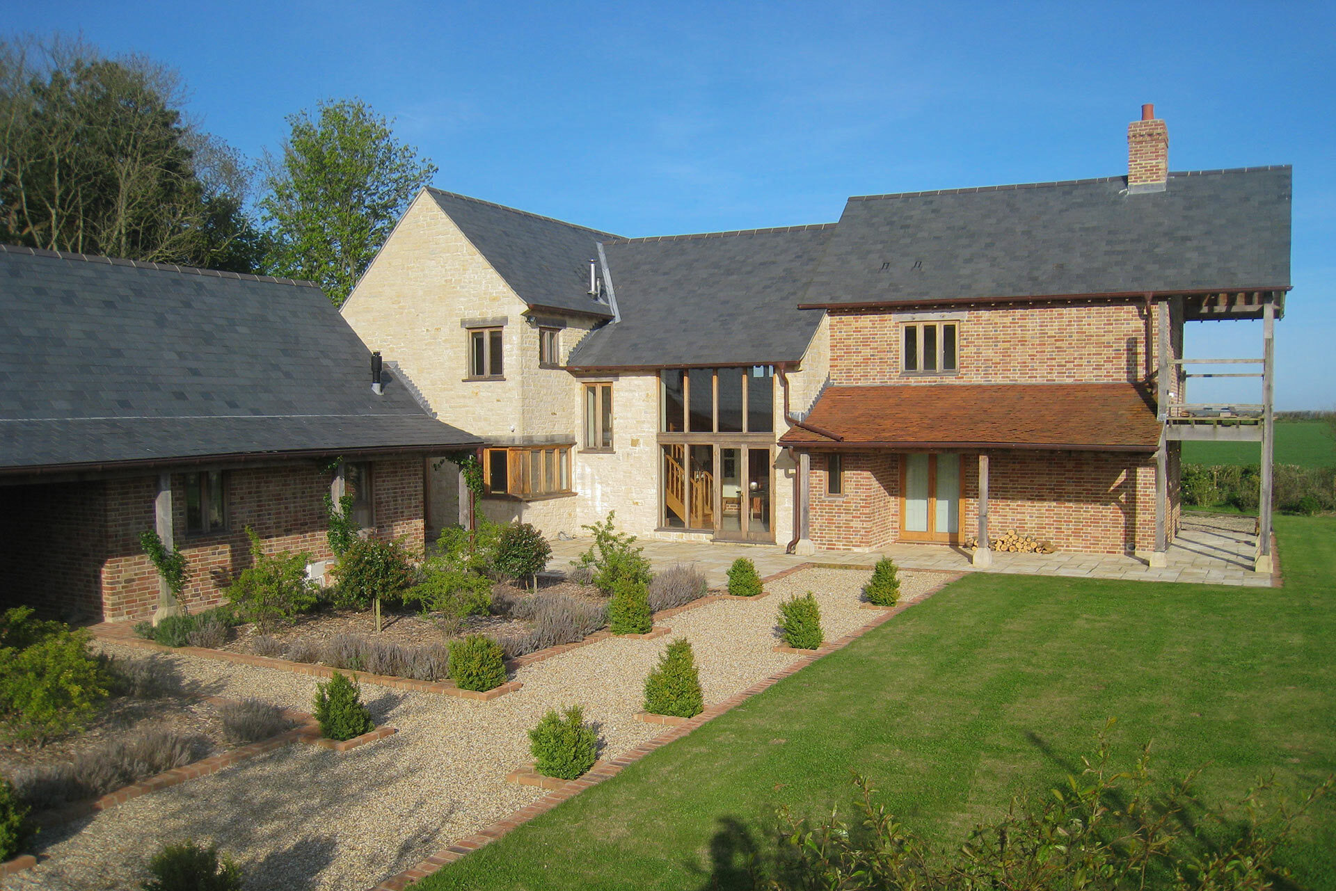 view of main entrance of large stone and red brick house from beautiful garden