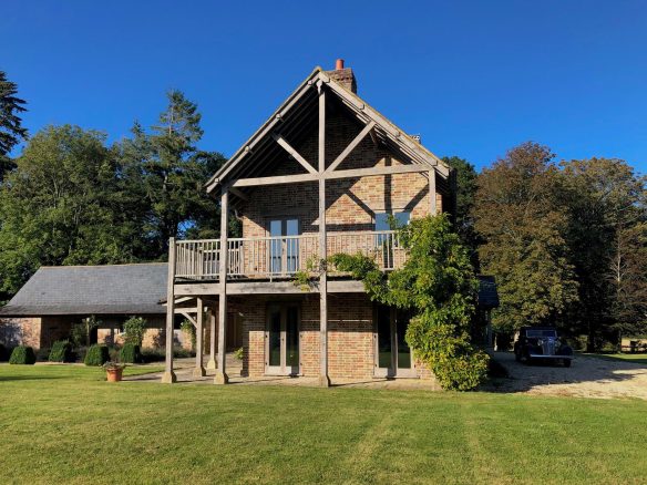 gable end of red brick house with large balcony and lovely garden