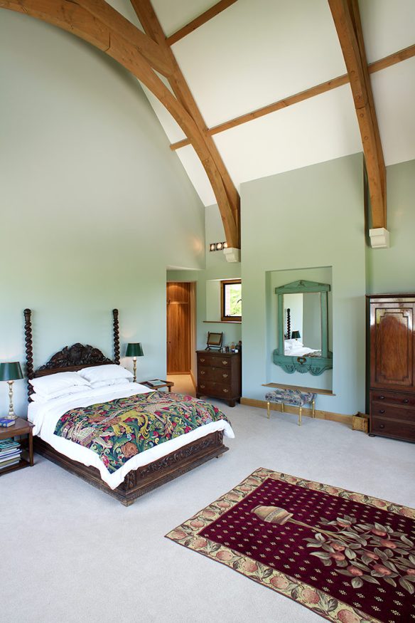 interior double height bedroom with green walls and exposed wooden beams