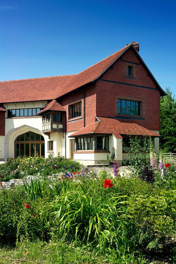 front view of stunning red and white house in daylight with flowers in front