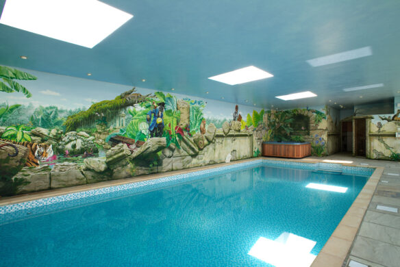 interior of indoor swimming pool with tropical mural on wall