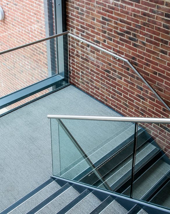 interior staircase with railings, red brick wall