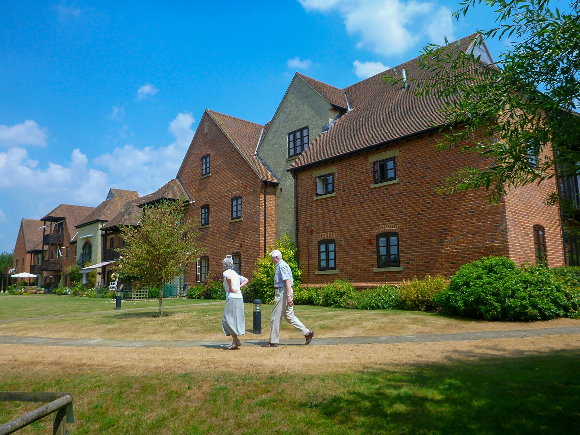 red brick retirement building in sunlight with lawn in front