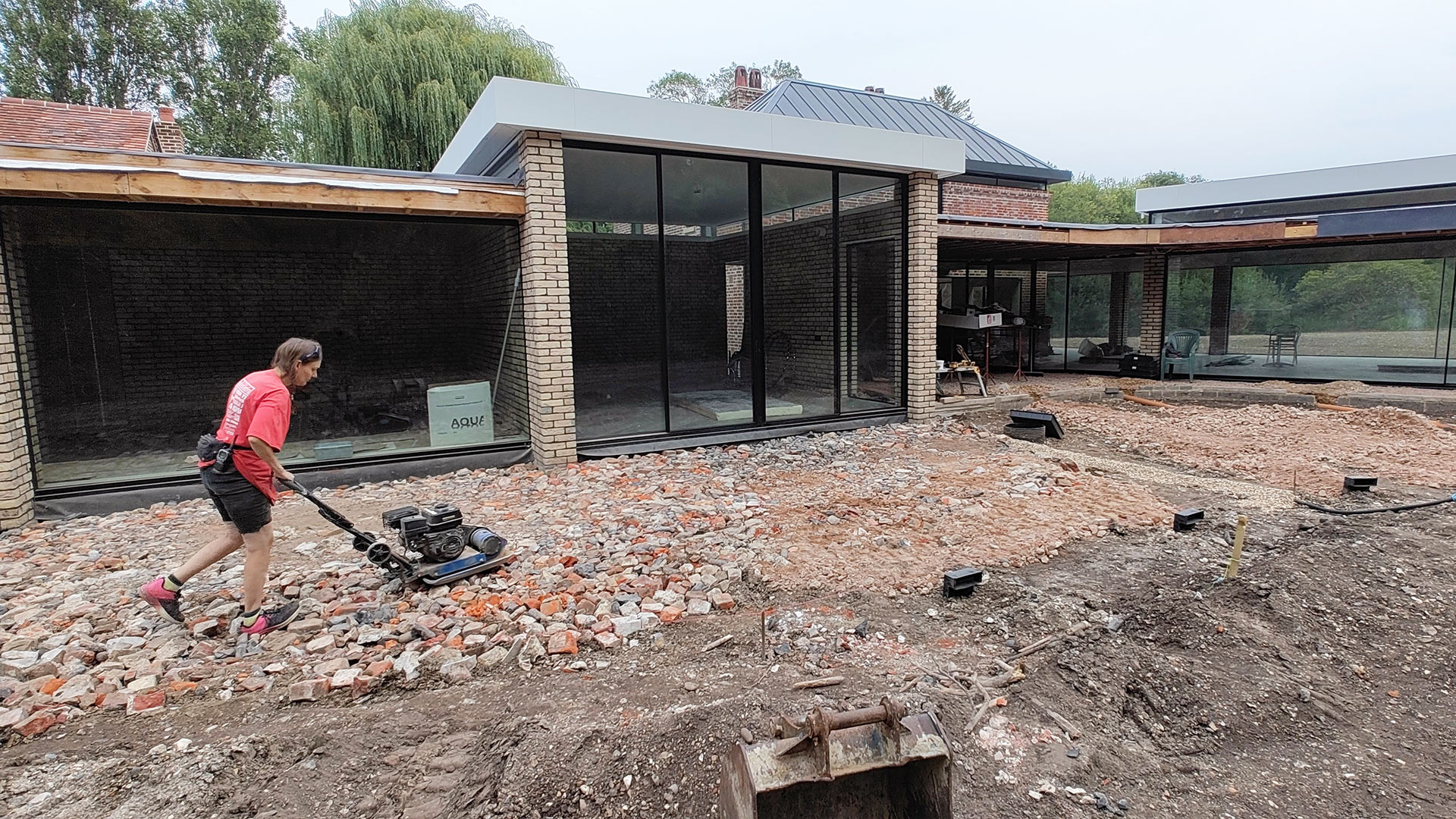 using reclaimed material to build garden area in front of house with large glass windows