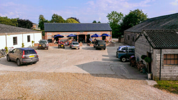 aerial view of converted barn with seating area and car park