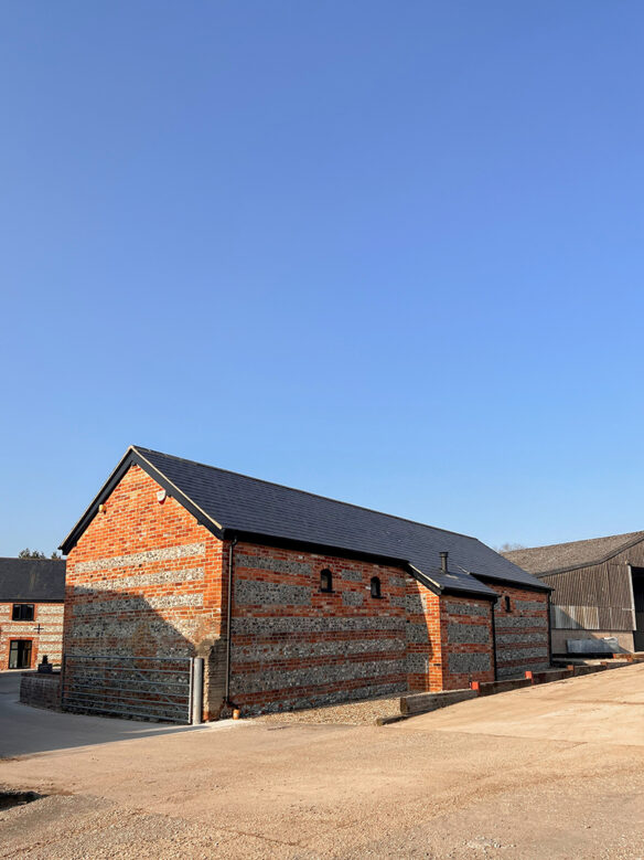 rear view of converted red brick barn with black roof
