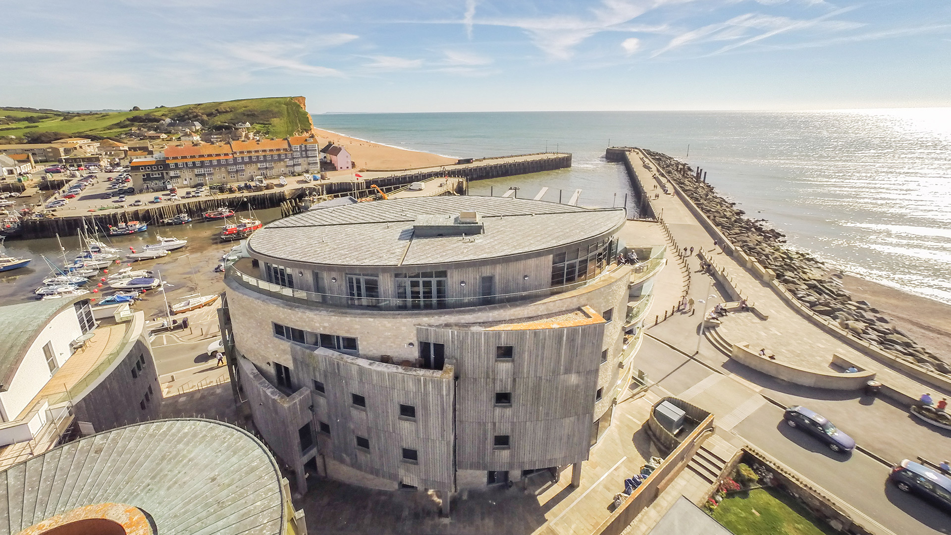 aerial view of circular building with wooden cladding and lovely sea views