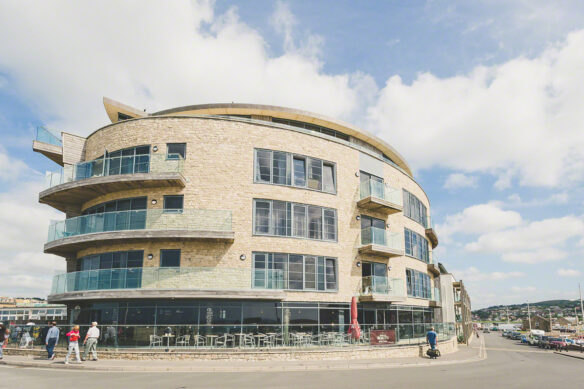 view of west bay apartments from road with café on ground floor