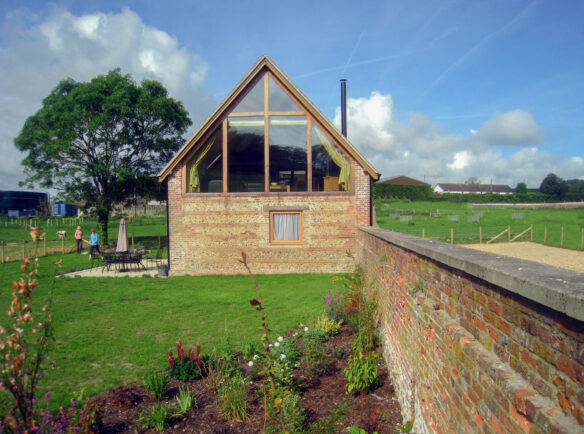 side view of brick shepherds hut with large windows in vaulted ceiling