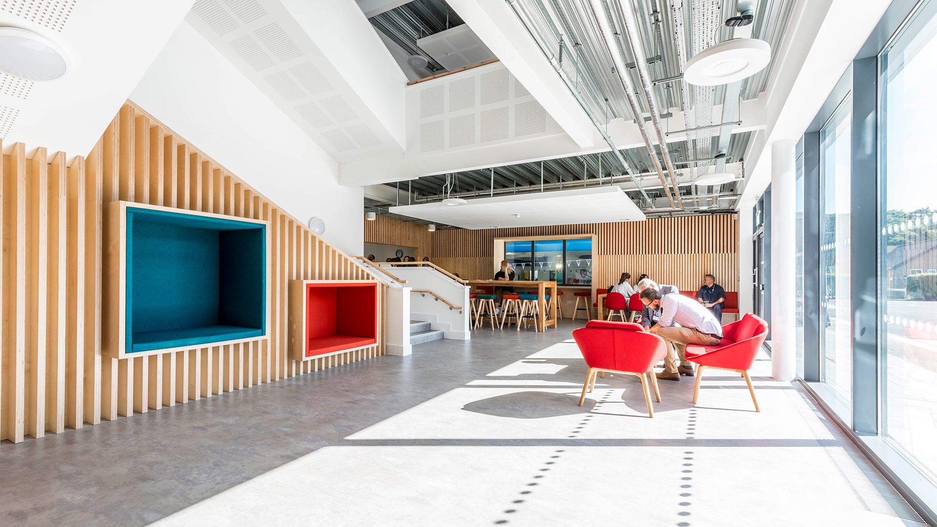 interior lobby and café seating area. Exposed pipework in ceilings and double height dogleg stairs overlooking ground level