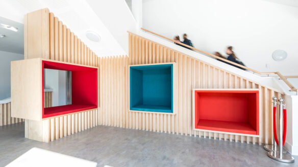 entrance blue and red seating pods built into the wall under the doglegged stairs