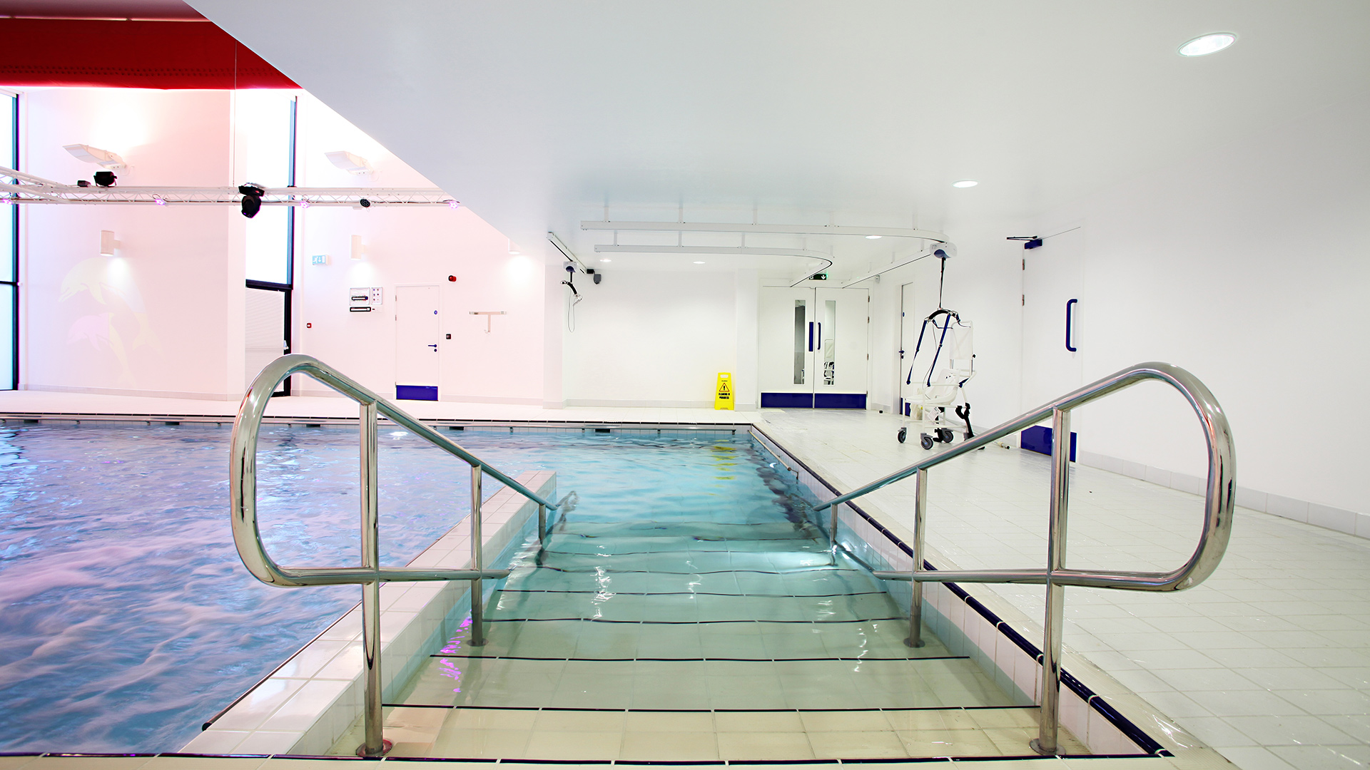 stairs leading into a hydrotherapy pool with accessible chair into pool in the background