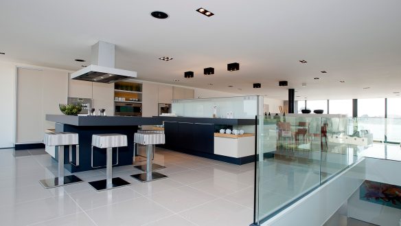 open plan kitchen in black and white colour theme with glass barriers around staircase