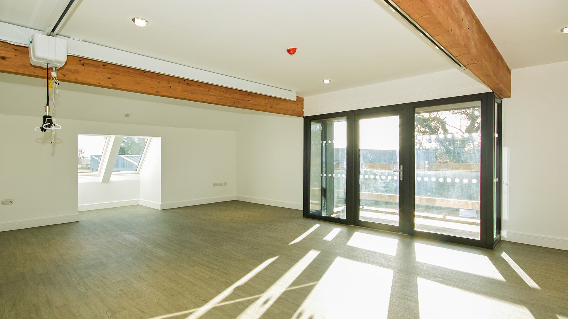 finished empty room with installed ceiling hoist and large glass door leading to balcony