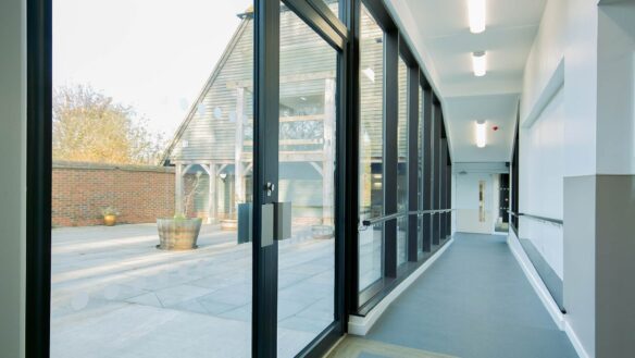 hall way with sloping floor and large glass windows looking onto courtyard area