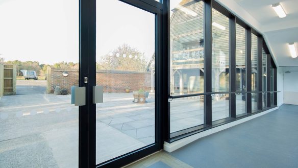 hall way with sloping floor and large glass windows looking onto courtyard area