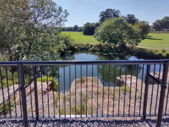 view from top of railway arches with railings looking down to river
