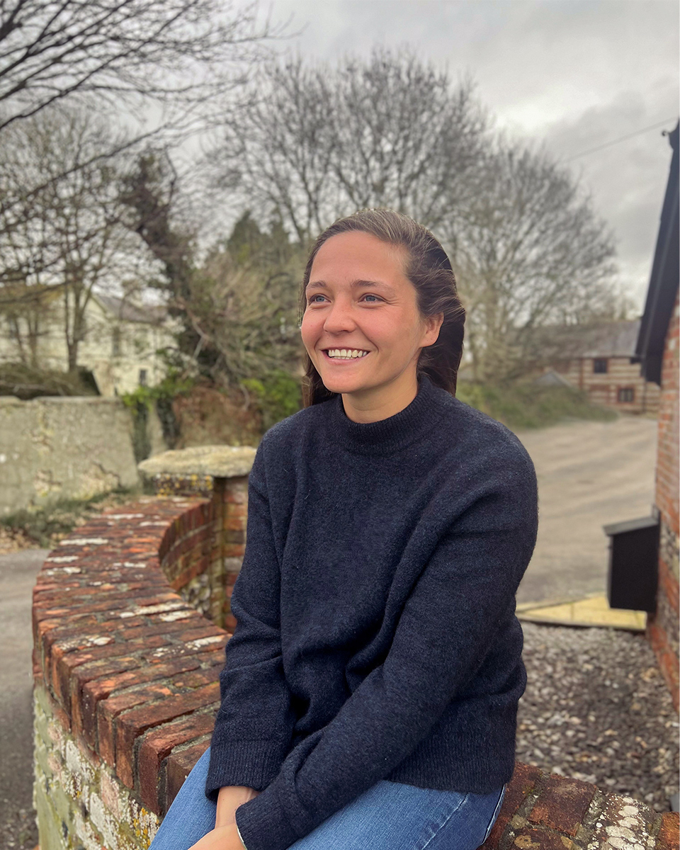 woman smiling sat on brick wall