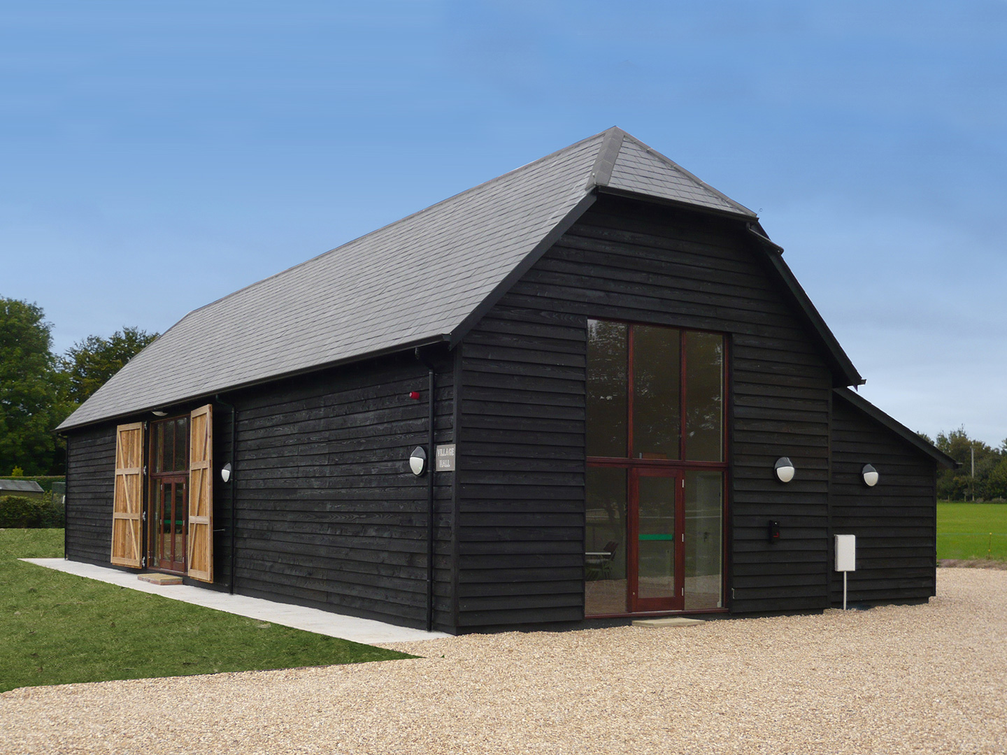 front view of large barn conversion with black wood cladding and double height windows