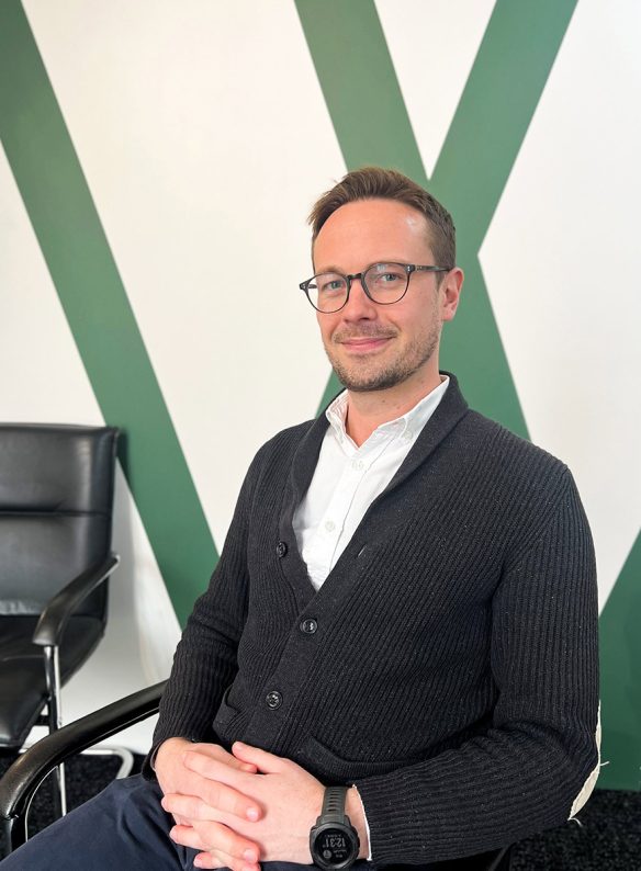 man smiling sat on chair with hands folded