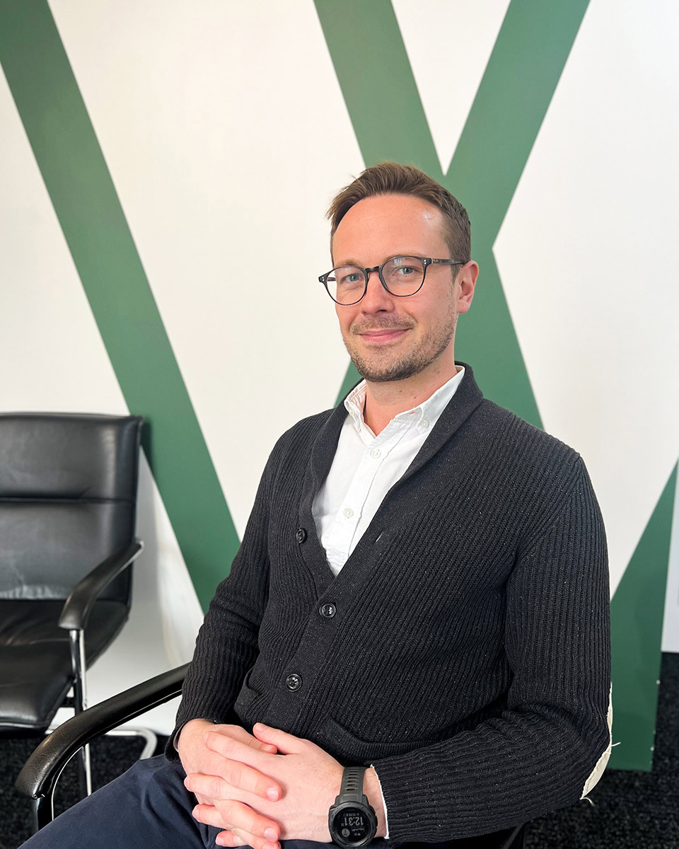 man smiling sat on chair with hands folded