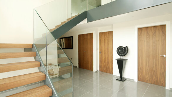 interior entrance hall of modern house with dog legged staircase and wooden doors