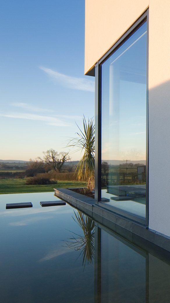 detailed view of side of modern white house with moat looking out to a beautiful countryside view