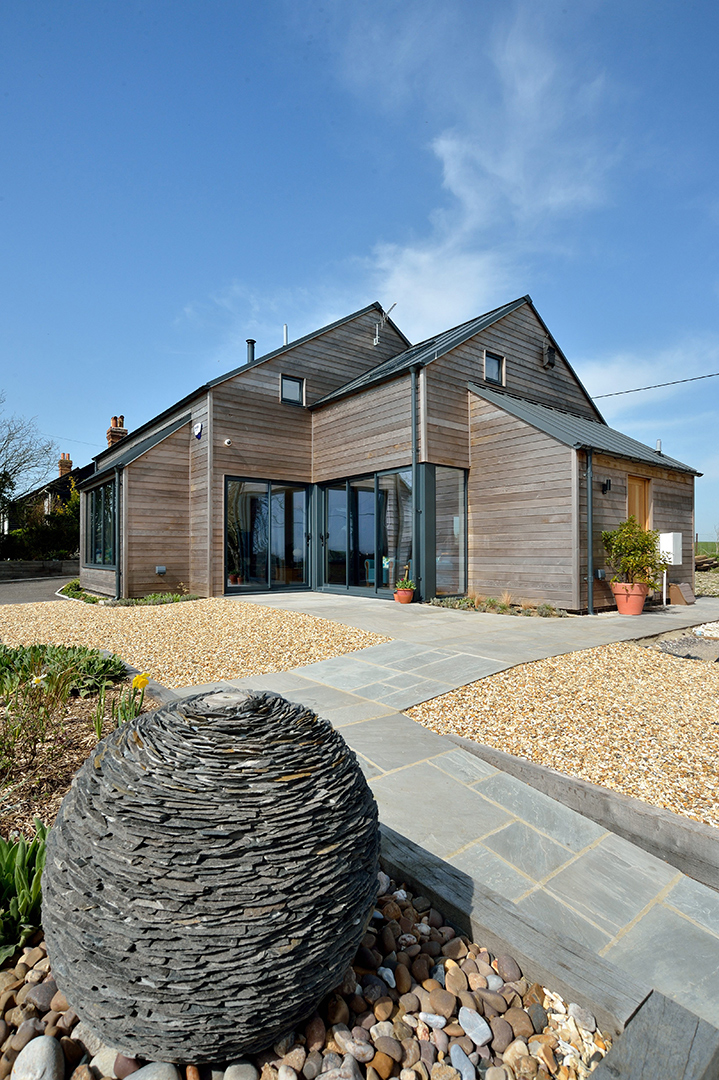 Modern rural house with timber cladding and metal roof view from rear garden